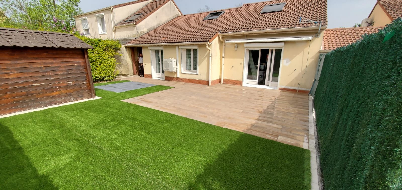 Terrasse en lames et pelouse devant une maison